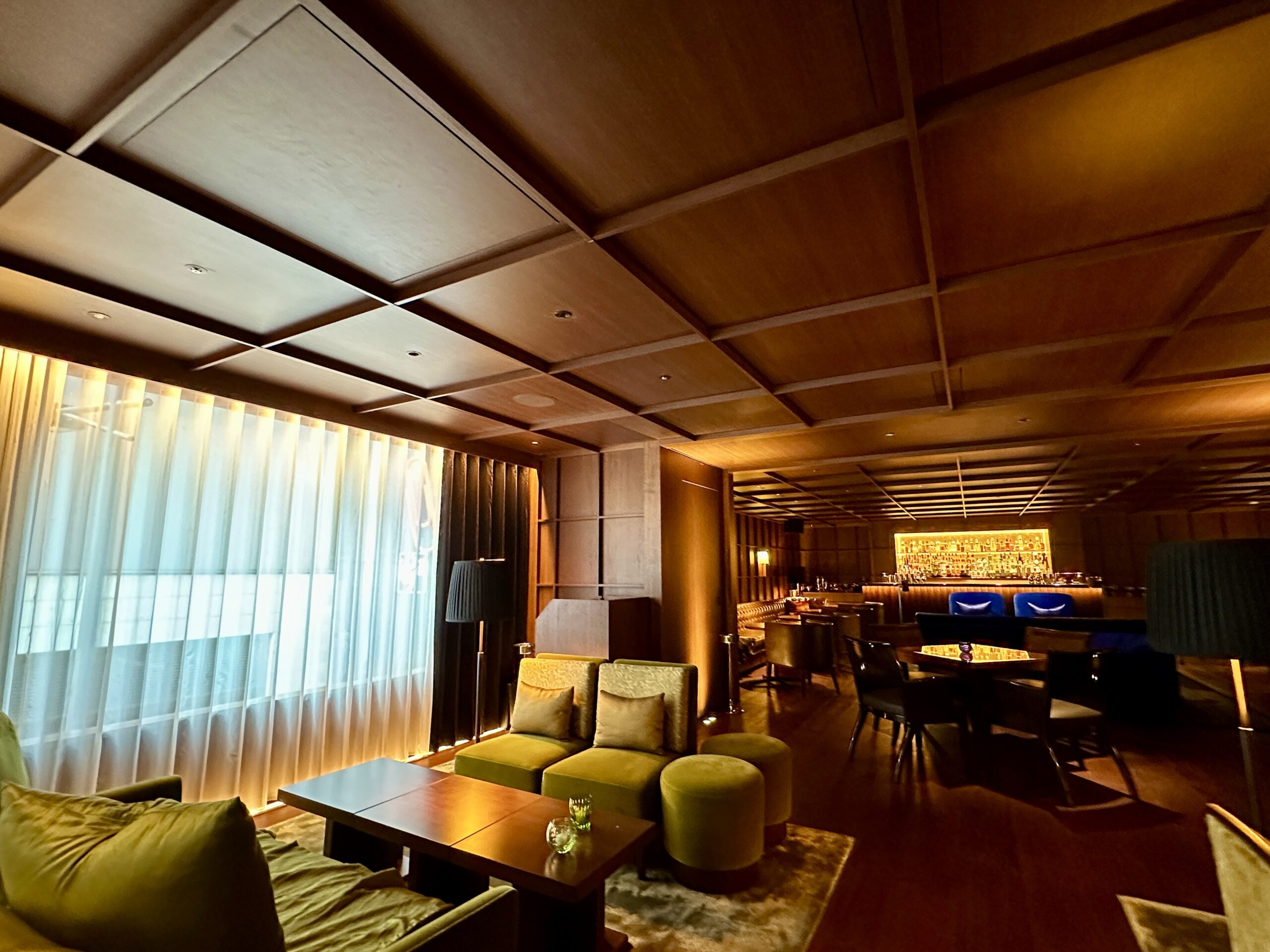 東京エディション銀座のシークレットバー「Punch Room」。木目の温かみと重厚なライティングが調和し、ベルベットのソファがアクセントとなる、銀座の隠れ家的な洗練された空間です。日本の伝統とモダンデザインが交差するこの場所は、着物を纏い、静寂と贅沢を嗜む大人のための究極の目的地といえます。
The secret bar "Punch Room" at The Tokyo EDITION, Ginza. This sophisticated hideaway features a harmonious blend of warm wood tones, ambient lighting, and elegant velvet sofa accents. It stands as an ultimate destination for adults to enjoy a serene and luxurious experience while wearing a kimono—a place where traditional aesthetics and modern design seamlessly intersect.