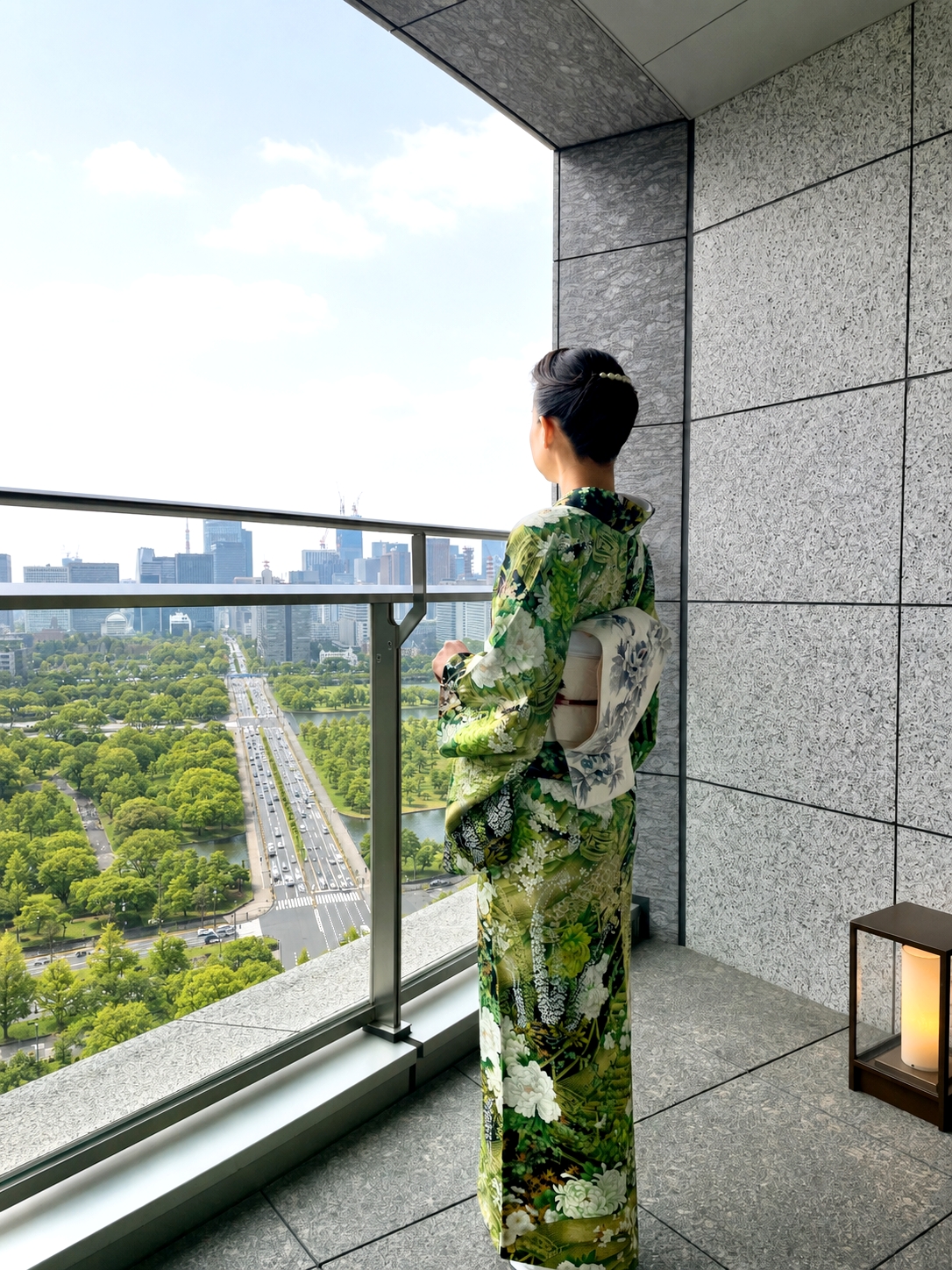 パレスホテル東京のテラスから皇居外苑を望む、花柄の染め着物を纏った女性。
Woman in a floral dyed kimono overlooking the Imperial Palace Outer Gardens from the terrace at Palace Hotel Tokyo