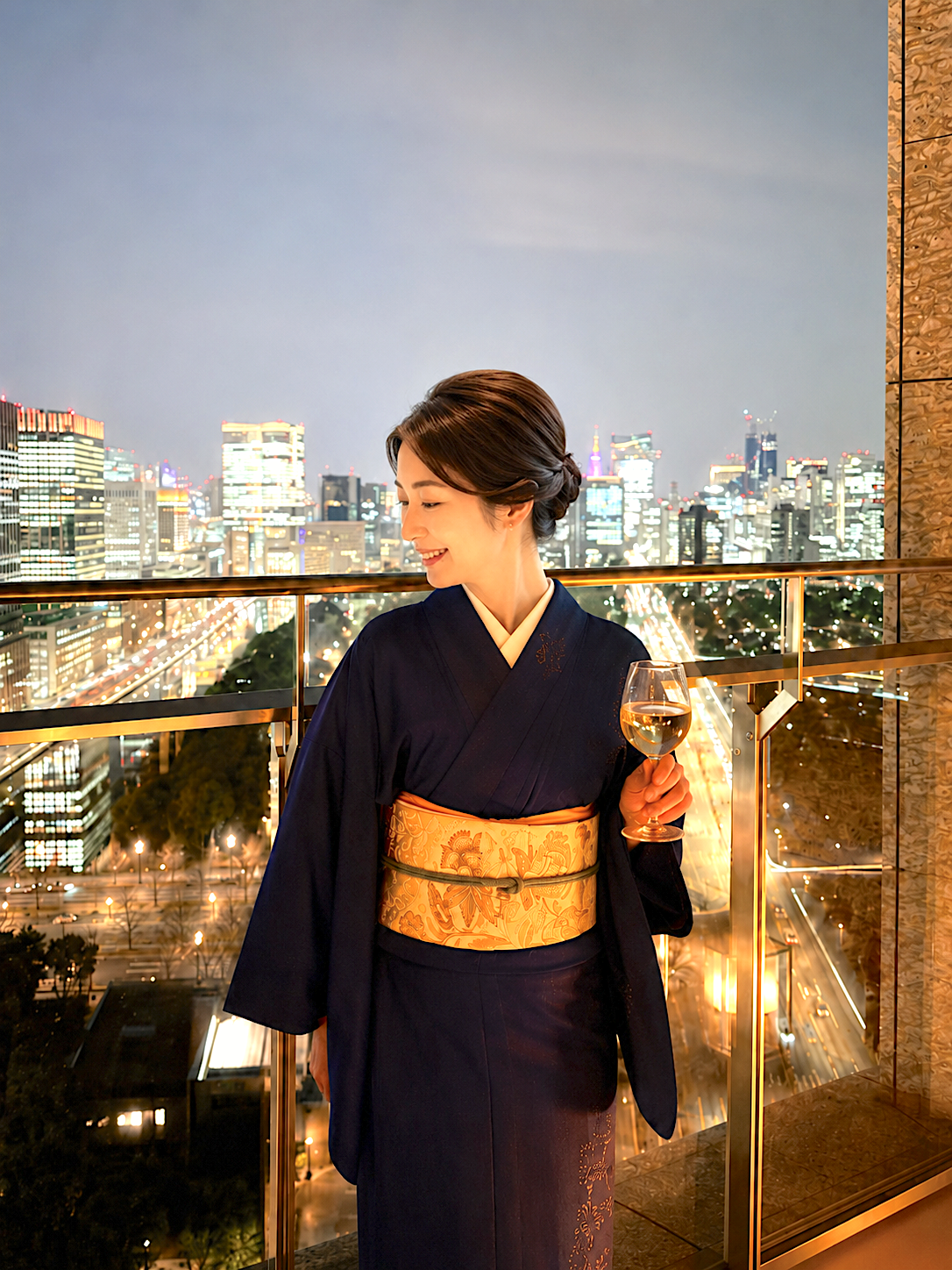 パレスホテル東京のテラス付きの部屋でワインを手に夜景を眺める、鳳凰文の着物を纏った女性。
Woman in a phoenix-pattern kimono enjoying Marunouchi night views with wine from the terrace at Palace Hotel Tokyo