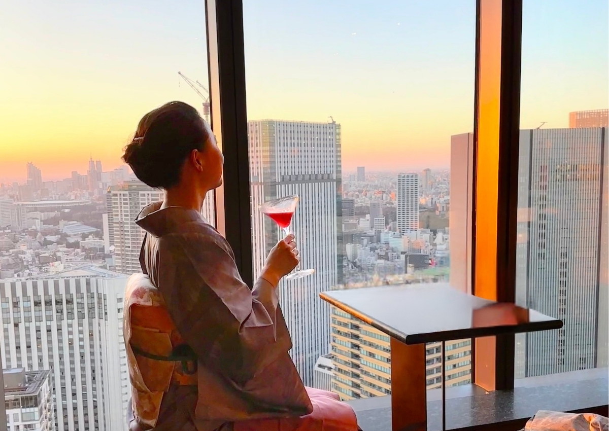 The Okura Tokyo 41階「バーラウンジ スターライト」で、夕景を眺めながらカクテルを愉しむ薄紫の大島紬姿の女性 A woman in a pale purple Oshima tsumugi kimono enjoying a cocktail at sunset at Bar Lounge Starlight on the 41st floor of The Okura Tokyo